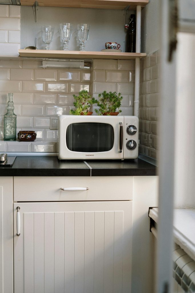 A cozy retro kitchen featuring a white vintage microwave and potted plants.